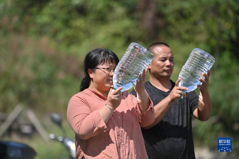 楊寧（左）在查看村民剛剛采集的水樣，為山泉水引水工程做準(zhǔn)備（10月8日攝）。新華社記者 黃孝邦 攝